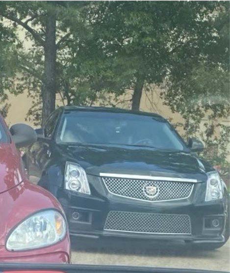 Photo of front side of black Cadillc CTS sedan, no license plate. 